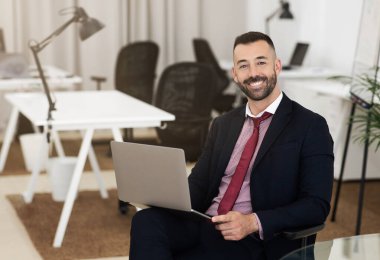 Takım elbiseli, kendine güvenen beyaz, olgun bir erkeğin iş yerinde dizüstü bilgisayar kullanmasına, sohbet etmesine ve ders çalışmasına sevindim. Öğretmen, işadamı, yönetici işi, iş hayatı, finans