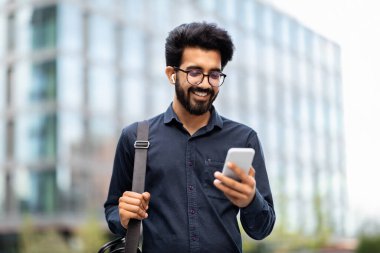 Mutlu, sakallı, sıradan ve gözlüklü bir genç adam ofise gidiyor, sokak sokak yürüyor, e-postaları kontrol ediyor, iş telefonu uygulaması kullanıyor, gülümsüyor, boşluk kopyalıyor.