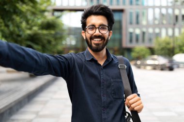 Resmi kıyafetli, gözlüklü, sokakta selfie çeken başarılı iş toplantısını kutlayan neşeli, yakışıklı, genç bir doğu girişimcisi. Hintli bir adam iş buldu, mülakattan sonra yürüyor.