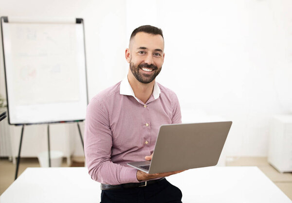 Glad confident attractive caucasian mature man in shirt use laptop in coworking office interior with board. Teacher and study remotely, businessman and business with gadget, manager work, lifestyle