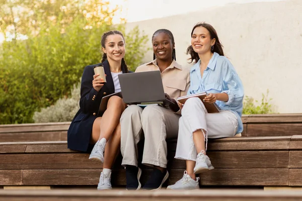 三个多文化的女生在大学校园休息 快乐的年轻女子在大学休息 坐在楼梯上 喝外卖咖啡 使用笔记本电脑 — 图库照片
