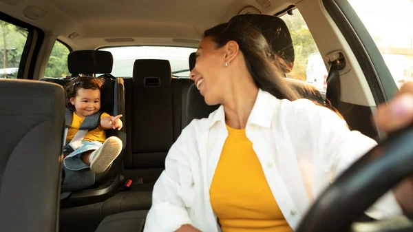 和妈妈一起开车 快乐的亚洲小孩儿女儿坐在婴儿座位上 一边开车一边指指点着妈妈 有选择地关注日本幼儿享受安全的汽车旅行 — 图库照片