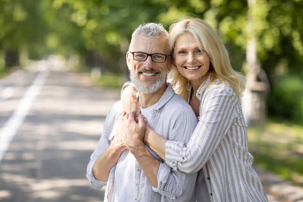 Портрет романтической зрелой пары, позирующей на открытом воздухе в летнем парке, любящих старших супругов, обнимающихся и улыбающихся перед камерой, счастливых пожилых мужчин и женщин, наслаждающихся свиданием на улице, копирующее пространство