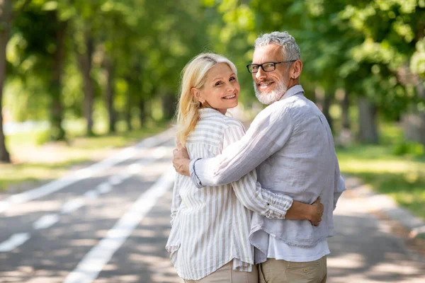 在夏天的公园里散步时 幸福成熟的夫妇拥抱在一起 年长的夫妇在镜头前拥抱和转身 老年男女在户外享受浪漫的约会 复制空间 — 图库照片