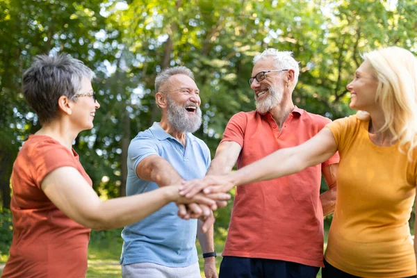 Group Motivation. Happy Senior People In Sportswear Stacking Hands After Training Outdoors, Cheerful Mature Men And Women Greeting Each Other With Successful Teamwork, Enjoying Active Lifestyle