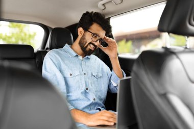 Lüks arabada kötü haber alan Hintli adamın portresi. Aracın içinde dizüstü bilgisayar kullanan üzgün bir doğu işadamı. Uzak işyerindeki proje sonuçlarından dolayı hayal kırıklığına uğramış profesyonel duygular
