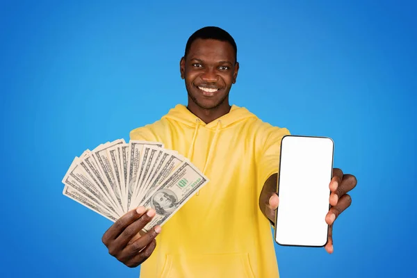 快乐的千年非洲裔美国人展示手机与空白屏幕 很多美元的钱 孤立在蓝色工作室的背景 App Device Website Online Shopping Sale Banking — 图库照片