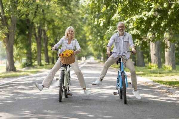 快乐的老夫妇在夏季公园骑自行车 快乐的成熟男女在一起玩乐 年长的夫妇骑复古自行车 享受积极的退休生活 复制空间的肖像 — 图库照片