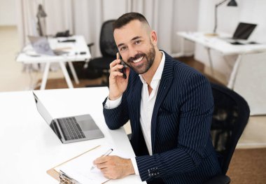 Gülümseyen beyaz, takım elbiseli olgun bir adam masaya oturur, dizüstü bilgisayar kullanır, telefon görüşmeleri yapar, ofis içinde notlar alır. İş adamı işi ve iş hayatı, başlangıç ve iletişim
