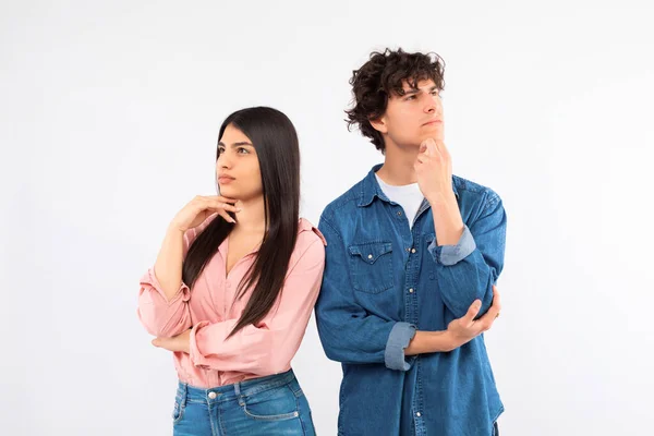 Let us think. Portrait of pensive hispanic young teens couple thinking and looking aside, touching chin, standing over white studio background. Thoughtful young lady and guy making decision