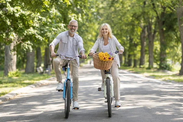 退休生活方式 快乐的老年配偶在公园里一起骑自行车 快乐的成熟男人和女人骑着复古自行车 在相机前微笑 有欢乐的户外 复制的空间 — 图库照片