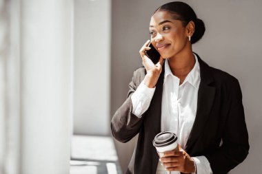 Zeki, gündelik içki içen, elinde kağıt bardakla telefonda konuşan, ofis içi fotokopi çeken, mutlu siyah girişimci.
