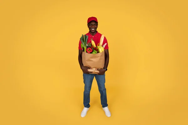 Sonriente Millennial Chico Afroamericano Mensajero Uniforme Sostener Bolsa Papel Con — Foto de Stock