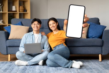 Harika bir uygulama. Neşeli Koreli Genç Eşler Evde dizüstü bilgisayarla dinlenirken Boş Akıllı Telefon Ekranı 'nı gösteriyor, Gülümseyen Asyalı Çift Yeni Uygulama veya Web Sitesi, Kolaj