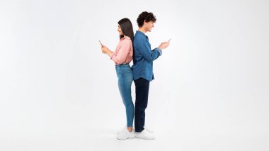 Bağlı Bağlı Online. Mutlu Öğrenci Genç Çiftler Cep Telefonu Kullanıyor, Sosyal Medya Kucaklıyor, Smartphone 'larında İnternet Mesajlaşıyor ve Taranıyor, Beyaz Arkaplanda Stüdyoya Dönüş Pozu Veriyorlar. Panorama