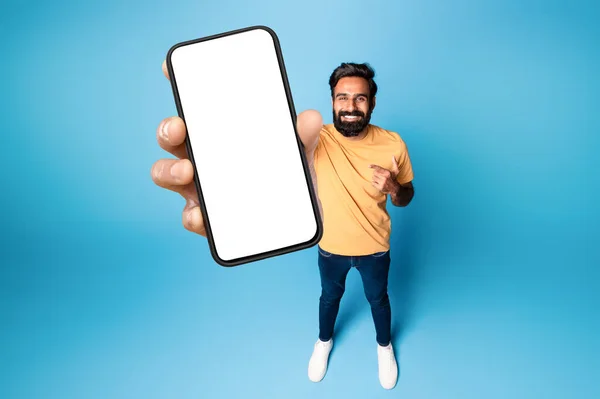 Веселый Индиец Держит Мобильный Телефон Белым Пустым Экраном Указывая Пустой — стоковое фото