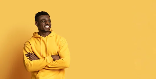 陽気なハンサムな若い黒人男性は コピースペースを見て胸に交差し 素敵なオファーをチェック 黄色の背景 パノラマを扱う — ストック写真