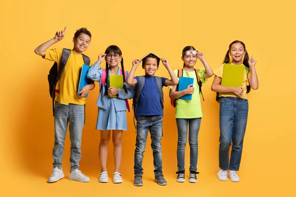 Šťastné Děti Multiraciální Žáci Batohy Zápisníky Rukou Šklebí Gestikuluje Žlutém — Stock fotografie