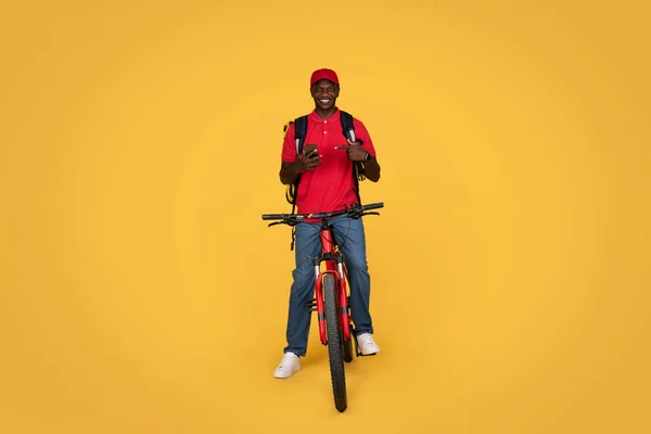 Sonriente Milenario Afroamericano Chico Mensajero Uniforme Con Mochila Bicicleta Dedo — Foto de Stock