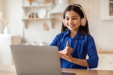 E-Öğrenme Onayı. Neşeli liseli kız dizüstü bilgisayar kullanıyor, web konferansını onaylıyor bilgisayarında eğitici çevrimiçi kurslar alıyor, modern iç mekanlarda internet okuyor ve internette geziniyor.