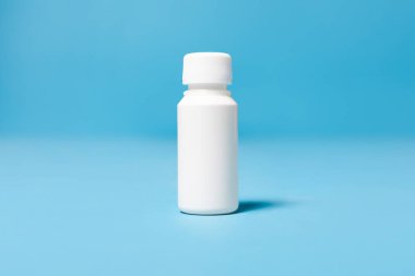 Kapalı beyaz bir şişe beyaz tıbbi plastik. Mavi stüdyo arka planında 100 ml izole edilmiş. Tasarım, metin ve reklam için model alan.