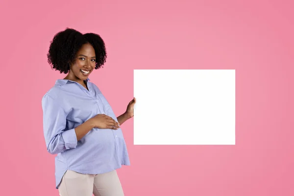 高兴的年轻的黑人孕妇在随意触摸大肚子 享受母亲展示横幅与空白 孤立在粉红工作室的背景 母亲保健 — 图库照片