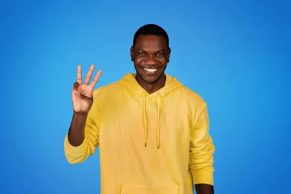 Sonriente Millennial Afroamericano Chico Sudadera Amarilla Muestran Tres Dedos Signo —  Fotos de Stock