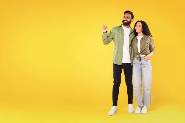 これを見てください 陽気なアラビア人男性と女性は 黄色の背景に指を指して指を指します あなたの広告のためのコピースペースを示す幸せな若い中東のカップルの完全な長さのスタジオショット — ストック写真