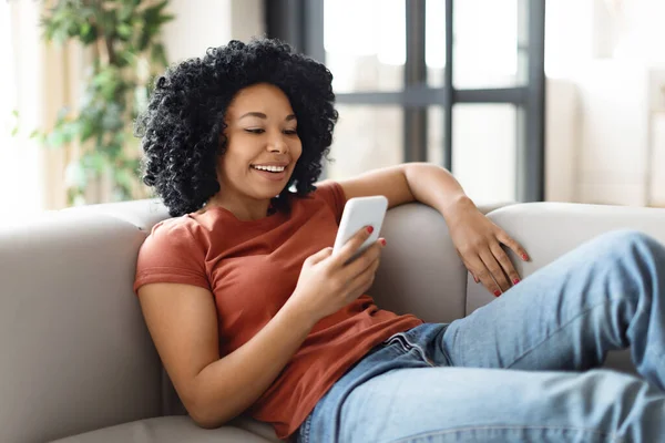 Evdeki Koltukta Dinlenirken Akıllı Telefon Kullanan Gülümseyen Siyah Kadın Cep — Stok fotoğraf
