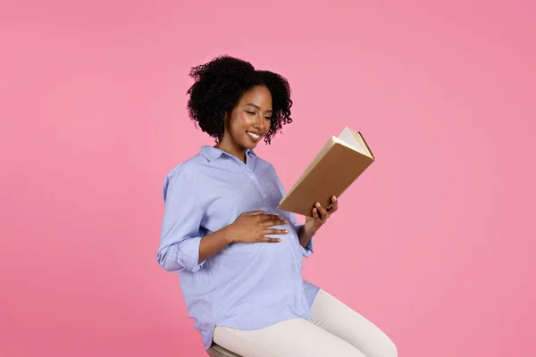 笑年轻的黑人孕妇在休闲与大腹部读物 孤立在粉红工作室的背景 母亲保健 生活方式 休息和放松 学习和教育 — 图库照片