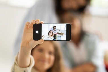 Gülümseyen Kafkas ergen kız, bin yıllık kadın ve yaşlı büyükanne telefon ekranında selfie çekiyorlar, oturma odasında boş vakitlerin tadını çıkarıyorlar, bulanık. Sosyal ağlar için fotoğraf, aşk, evdeki ilişki