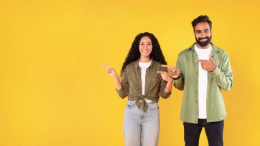 Teklifi kontrol et. Fotokopi Boşluğu 'nu gösteren, reklam metni için boş bir yer gösteren, Stüdyo, Panorama' da sarı arkaplan üzerinde duran mutlu Arap genç çift.