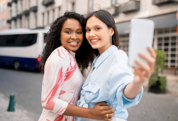 Duas Amigas Alegres Com Smartphone Tirando Selfie Enquanto Caminham Livre — Fotografia de Stock