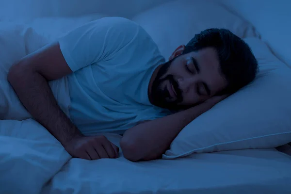 건강한 침대에 누워있는 남자의 초상화 침실에서 휴식을 어두운 방에서 손으로 — 스톡 사진