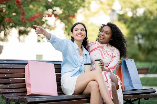 两个漂亮的女性朋友购物后放松一下 坐在长椅上喝咖啡 快乐的年轻女人在外面购物时一起玩乐 女士指指点迷津 — 图库照片