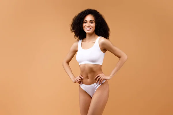 stock image Happy slender latin lady posing in white underwear, showing her beautiful figure over brown studio background, copy space. Diet, athletic body concept