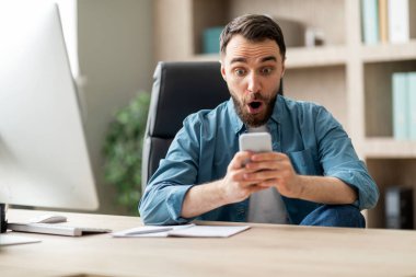 Harika bir teklif. Ofiste Smartphone Screen 'e Şok Olan Genç Adamın Portresi, Masasında oturan ve Şok Olan Genç İşadamı, Beklenmedik Mesaj Okurken, Kapanış
