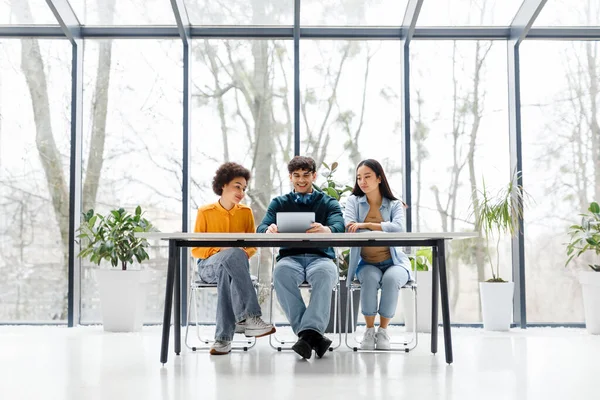 stock image Happy multiracial students using tablet, watching educational videos online or surfing internet, sitting at table indoors, full length, free space. Online knowledge