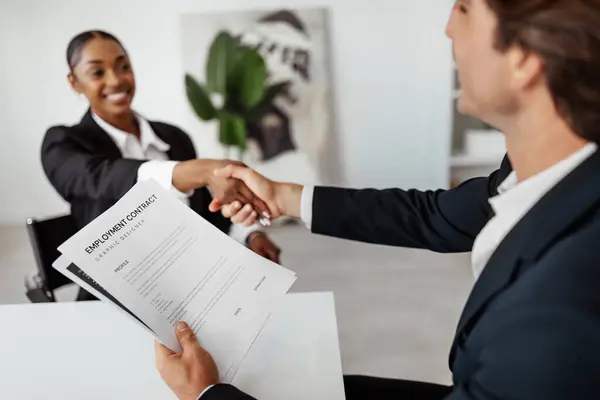 stock image Successful job interview. Hired black female candidate seals the deal with the HR team recruiter by handshaking after signing employment contract