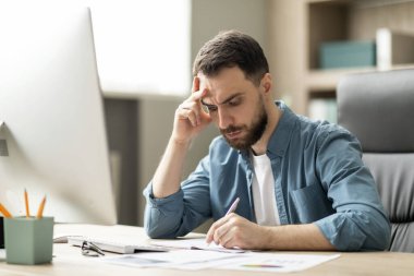 Odaklanmış genç işadamı ofisinde oturuyor ve not defterine yazıyor, yakışıklı milenyum erkek girişimcisi iş yerindeki not defterine not alıyor, CEO 'su ajandasını kontrol ediyor, kapatıyor.