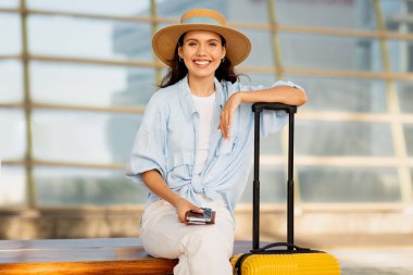 Bavullu genç Avrupalı bayan turist, akıllı telefon kullanıyor, yolculuğun tadını çıkarıyor, tren istasyonunda bekliyor. Trip, aktif yaşam tarzı, yazları aletlerle tatil