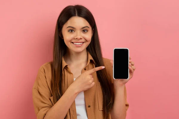 用空白的黑屏微笑着在手机上指点的少女 漂亮的少女推荐网上提供或在投递粉红工作室背景 调校时的新应用 — 图库照片