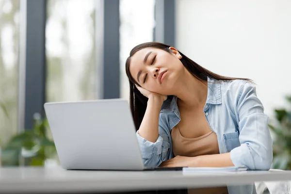 教育の疲労と過労について 疲れたアジアの学生女性は オンライン学習や授業に疲れたノートパソコンの前で寝て 屋内テーブルに座っています — ストック写真