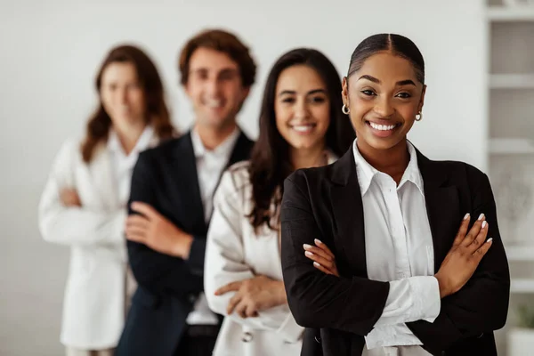 Successful business team. Happy multiethnic colleagues with black female boss posing in office, standing with folded arms in line and smiling at camera