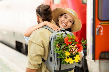Genç Avrupalı adam trendeki bayanla tanışıyor, sarılıyor, istasyonda çiçek veriyor. Turdan, turistik duygulardan, yaşam tarzından, yaz tatilinden, aşk ve ilişki duygularından dön.