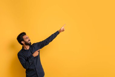 Şuraya bak. Fotokopi Uzayı 'nı işaret eden mutlu Hintli genç adam, Neşeli ve yakışıklı doğu erkek Reklam Tasarımı için bedava bir yer, Sarı Stüdyo Arkaplanının üzerinde duruyor.