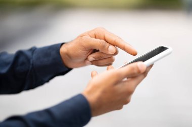 Açık havada siyah ekranlı cep telefonu tutan bir adam eli. Tanımlanamayan iş adamı akıllı telefon kullanıyor, güzel mobil uygulamalar gösteriyor, çevrimiçi teklif, taklit, kopyalama alanı öneriyor