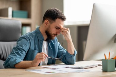 İş yerinde yorgun erkek girişimcinin portresi, Milenyum İşadamı Gözlüğünü çıkarıp Burun Köprüsü 'ne masaj yapıyor, Ofiste dizüstü bilgisayarla çalıştıktan sonra yoruldu.