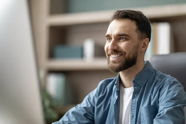 stock image Portrait Of Smiling Handsome Businessman Working On Computer In Office, Smiling Millennial Male Entrepreneur Sitting At Work Desk And Looking At Monitor Screen, Thinking About Business Ideas