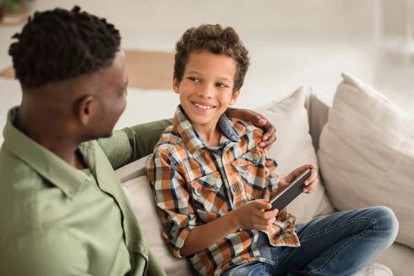 Loving Black Father Hugging Kid Son While Boy Using Smartphone — Stock Photo, Image